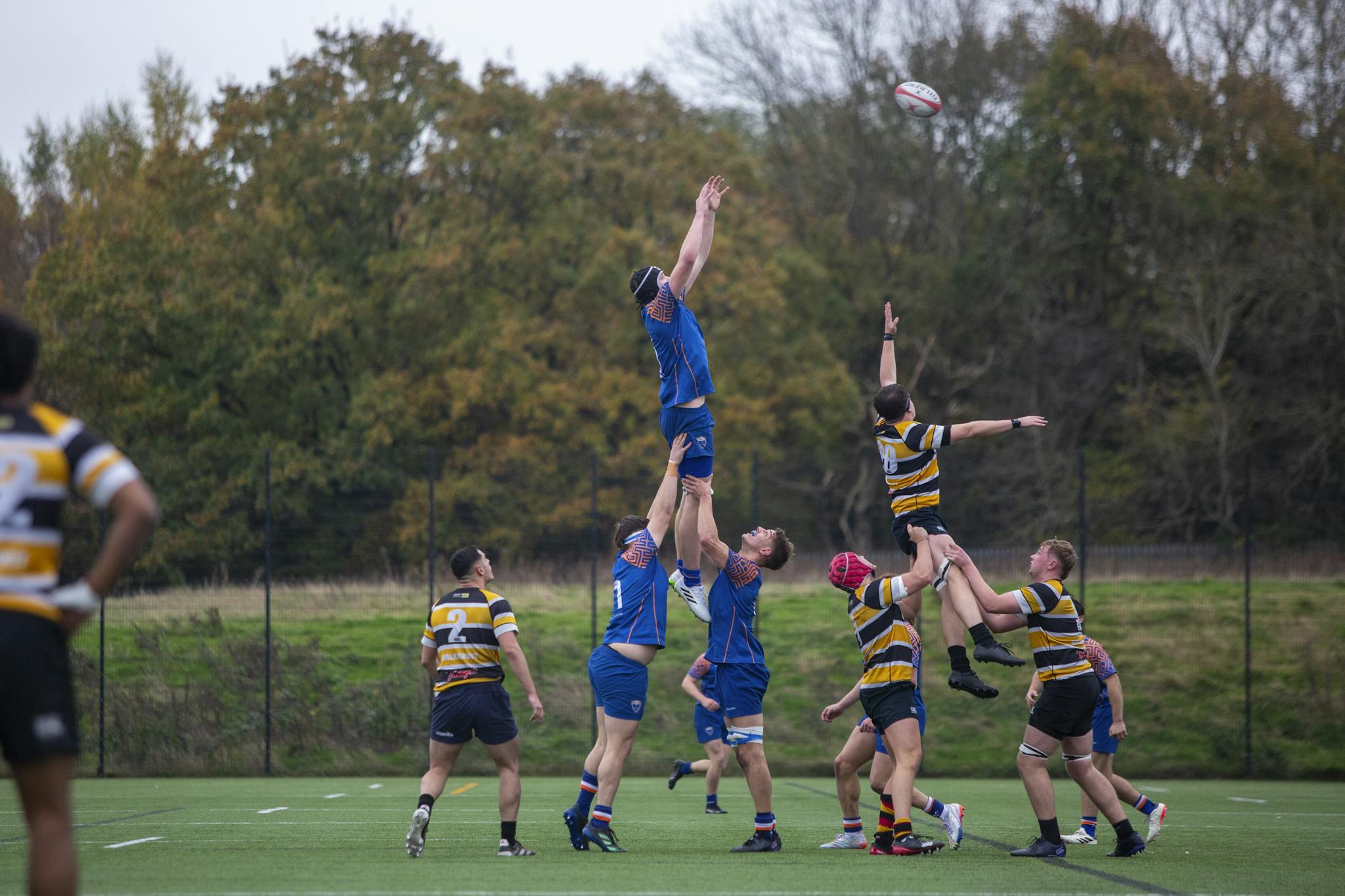 Intense college rugby match showcasing teamwork and athleticism on a vibrant fall day.
