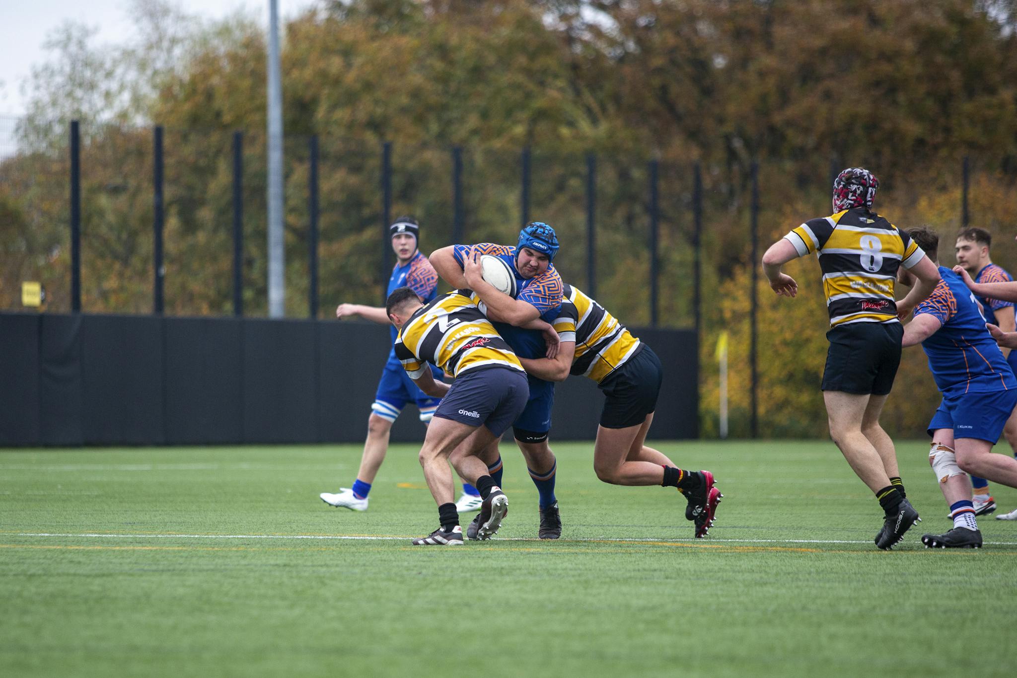 Rugby players in action during a competitive outdoor match in autumn.