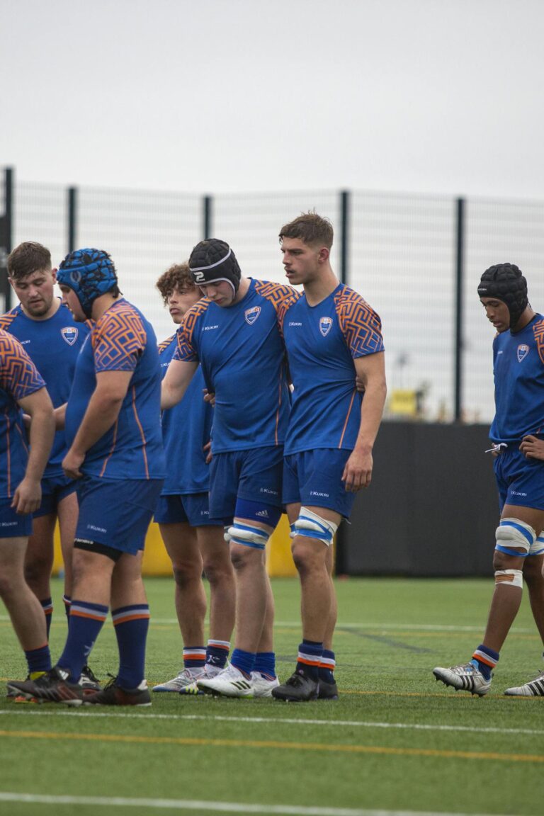 University rugby players gather on the field during a competitive match.