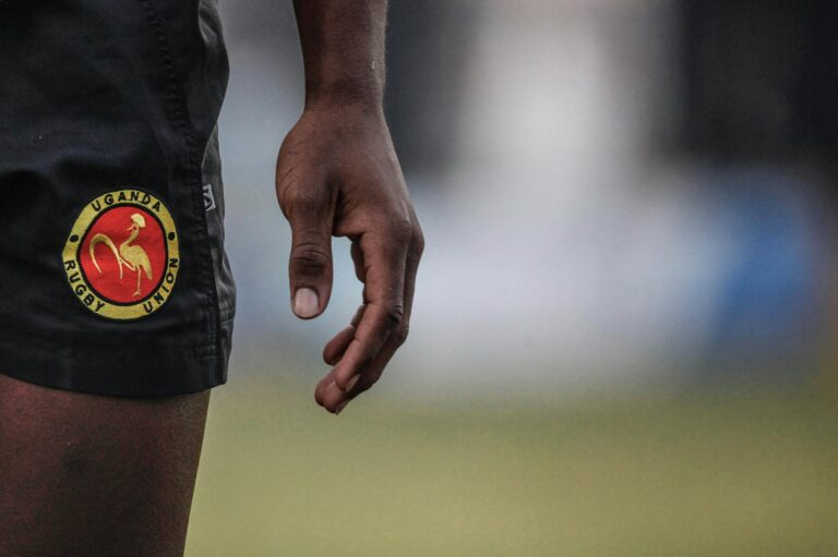 Zoomed-in view of Uganda Rugby Union shorts with an adult hand visible.