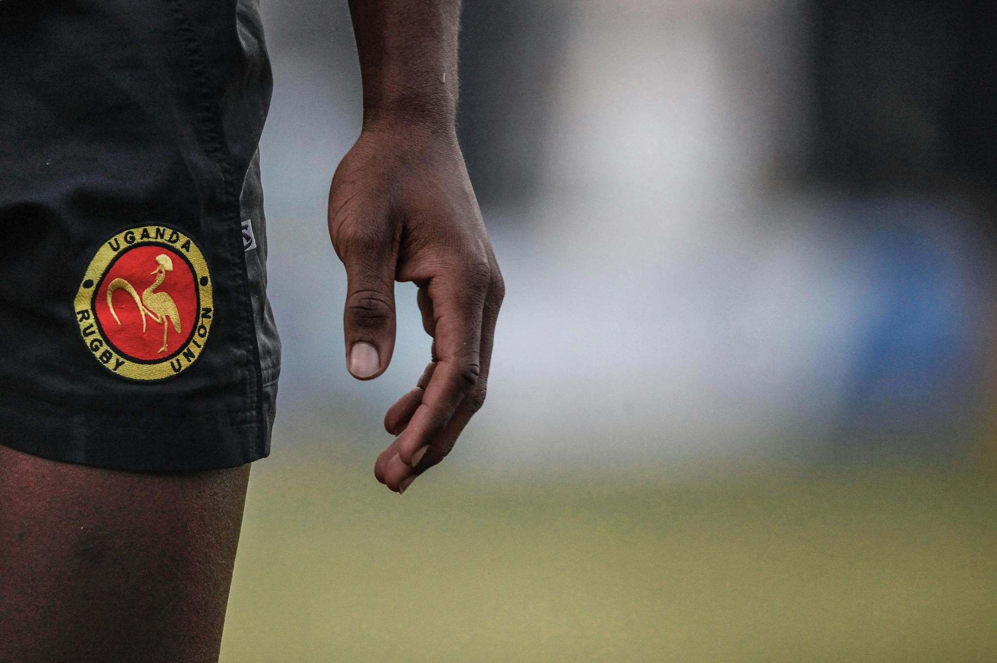Zoomed-in view of Uganda Rugby Union shorts with an adult hand visible.